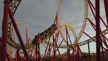 Rollercoaster Passengers Amusement Park Ride Looping Thrills. Aerial View, People enjoying a thrilling rollercoaster ride at an amusement park. video
