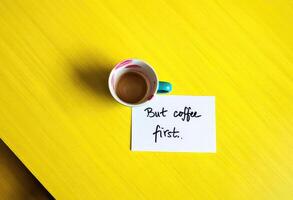 Enjoying coffee on a bright yellow table with a handwritten note about priorities photo