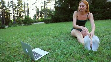 A girl stretches while taking online classes on her laptop in a public park video