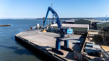 28 April 2025 Poole, Uk. Material handler unloading cargo in Poole Harbour, UK photo