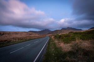 Serene Road Leading to Snowdonia Mountains at Dusk photo