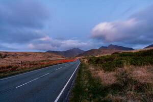 Car driving on scenic road at twilight in Snowdonia National Park photo