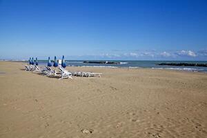 Deck chairs and parasols on an empty beach in winter on a sunny day photo