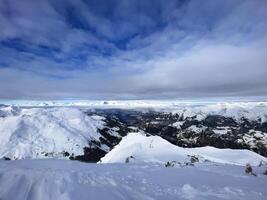 a view of the mountains from the top of a snow covered mountain photo