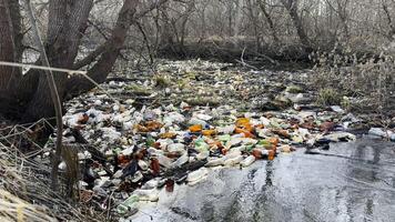Dirty river is polluted with many plastic bottles. A lot of trash is dumped in open and freely available places at nature. Global environmental pollution problem. Concept of ecological disaster. photo