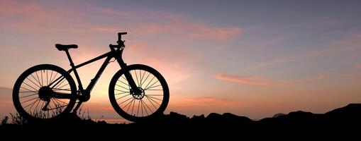 Silhouette of a Bicycle Against a Vibrant Sunset Sky in a Tranquil Outdoor Setting photo