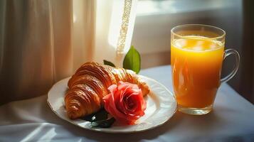 A croissant and orange juice on a plate photo