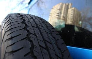 A multi storey building is reflected in the rear window of a car with a spare tire on the door photo