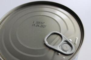 Top part of sealed tin of canned meat with an expiration date of 2027 isolated on white photo