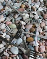 Silvery Forks From One Set Scattered On Small Colorful Pebbles photo