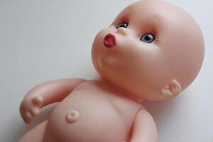 Baby Doll With Sad Eyes Lying On White Surface Detailed Stock Photo