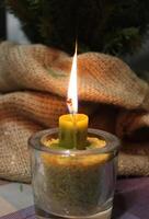 Traditional Candle Injected In Wheat Corns Inside Glass Burning In Front Of Spruce In Craft Folded Fabric photo