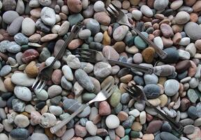 Same Three Pronged Forks Scattered On Smooth Sea Pebbles Top View Stock Photo