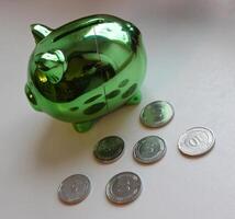 Cracks on a Side Of Piggy Bank With Scattered Coins photo