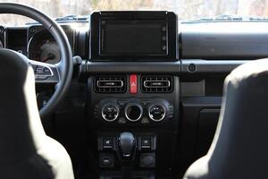 A look between the front seats at the panel with the climate system and the central display in the car interior photo