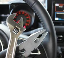Car Service Concept Image. Adjustable Spanner And Steel Pliers In Front Of Steering Wheel Inside Car photo