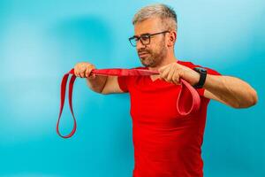 Man. exercises with resistance band against blue backdrop photo