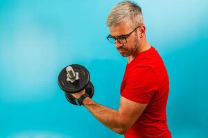 Man lifting dumbbell in bright blue gym setting photo