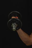 Individual lifts a dumbbell in a dark setting photo