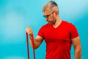 Man exercising with resistance bands against blue background photo
