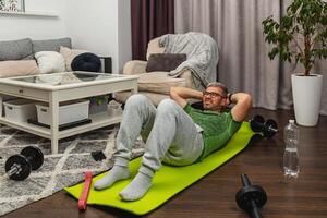 Man exercises at home using a yoga mat and weights photo