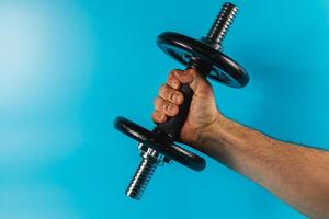 Lifting a dumbbell against a bright blue background photo