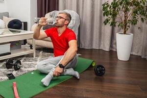 Man exercising at home while taking a water break photo