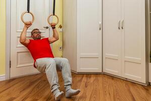 Man exercising with gymnastic rings in home gym area photo