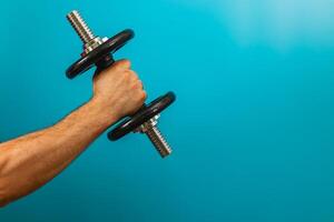 Lifting a dumbbell against a solid blue backdrop photo