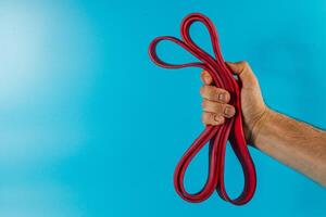 Holding red resistance bands against a blue background photo