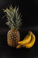 Fresh pineapple and ripe bananas on a dark background display natural colors photo