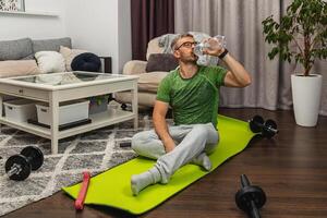 Man exercising at home while drinking water photo