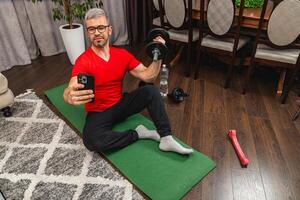 Man exercising at home while taking a selfie photo