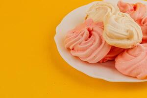 Colorful meringue cookies on a bright yellow plate photo