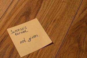 Inspirational note on wooden floor emphasizing the value of success photo