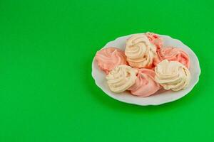 Colorful meringues arranged on a plate against a green background photo