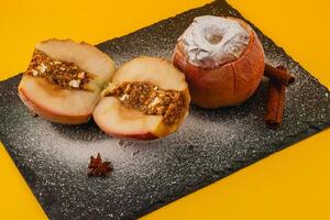 Baked apples with cinnamon and nut stuffing on a black slate photo