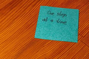 Motivational note on a wooden surface encouraging a steady approach to tasks photo