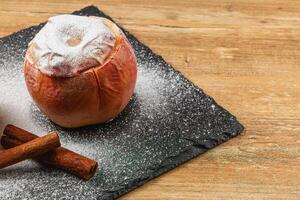 Baked apple dessert with cinnamon on a dark slate surface photo