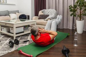 Man exercises indoors on mat in living room photo