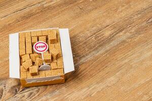 Brown sugar cubes in a box with a stop sign on a wooden surface photo