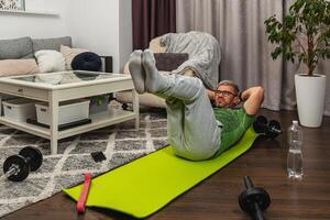 Man exercising at home on a green workout mat photo