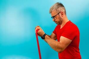 Man exercises with resistance. band against blue backdrop photo