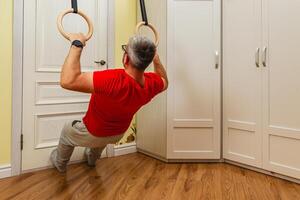 Man exercising with rings indoors for fitness routine photo