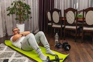 Man exercising at home on a green mat in the evening photo