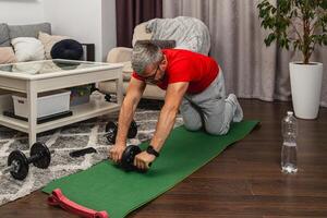 Man exercising at home using an ab roller on a mat photo