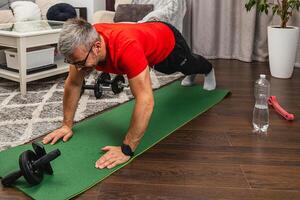 Man exercises at home on workout mat with dumbbells photo