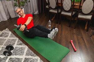 Man exercising at home with dumbbells and mat photo