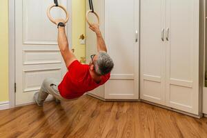 Man performs fitness exercise using rings at home photo