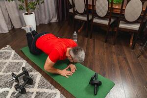 Man performs plank exercise indoors on yoga mat photo